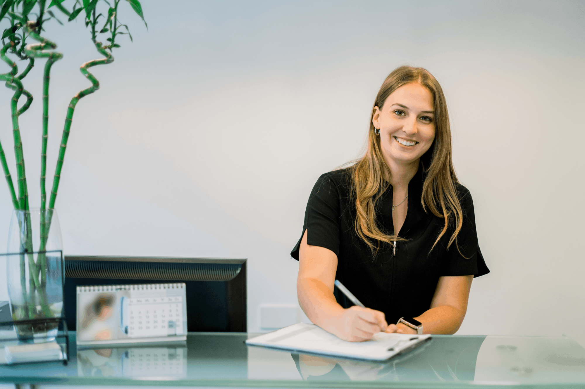 Beraterin sitzt am Schreibtisch und macht sich Notizen während eines Gesprächs.